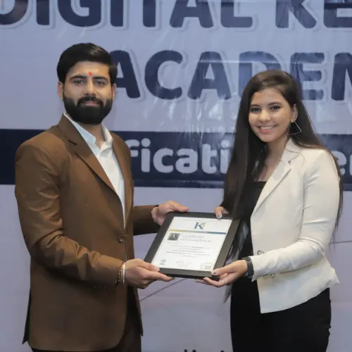 Two individuals exchange a certificate at a professional event, standing in front of a banner for a digital marketing institute in Surat, celebrating completion of a digital marketing course in Surat.